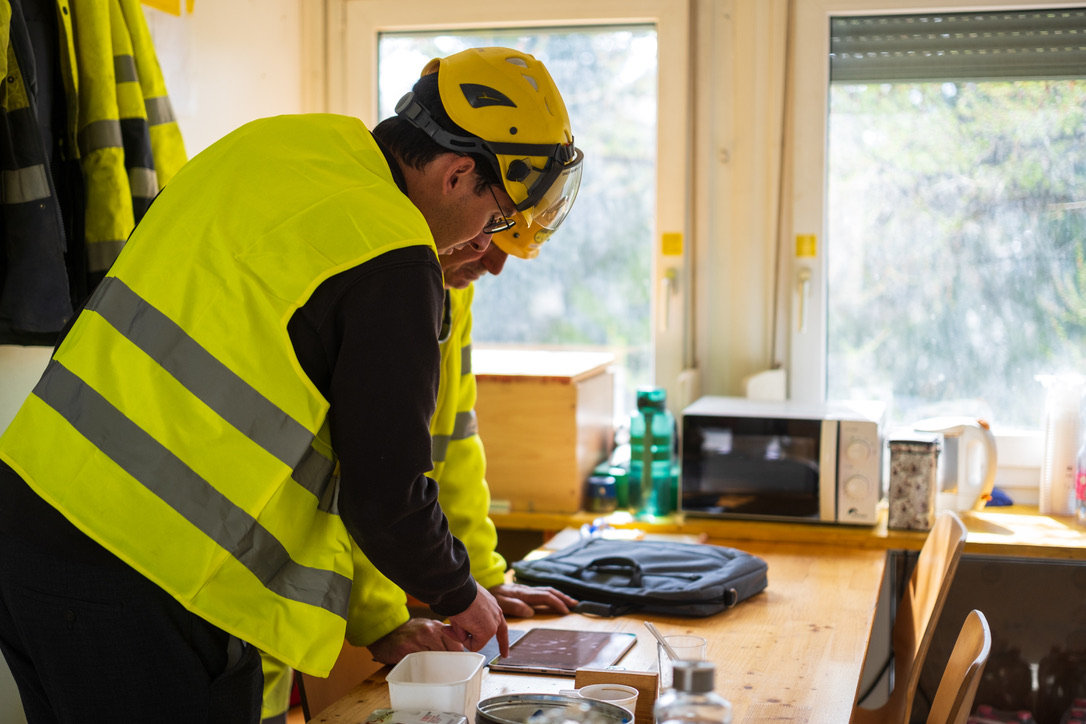 Collaborateurs casqués consultant les plans dans un baraquement de chantier